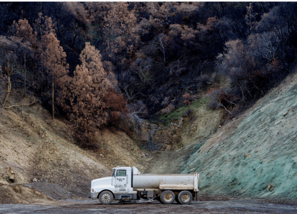 A photo of a truck in front of a hill