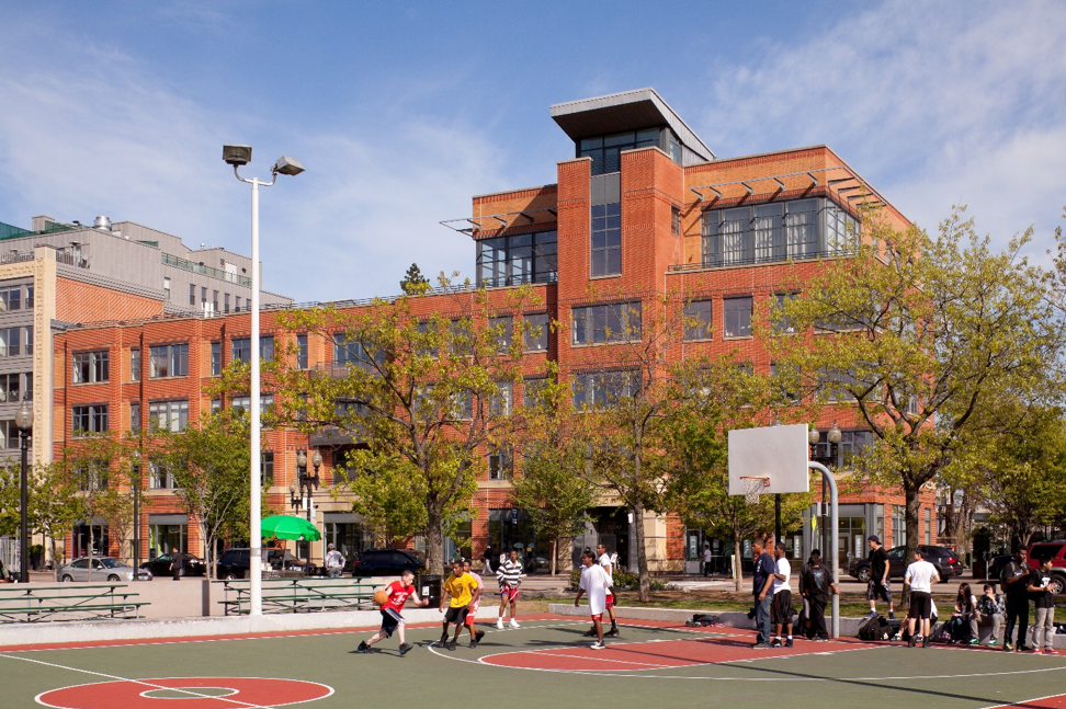 View of laconia lofts from peters park with kids playing basketball